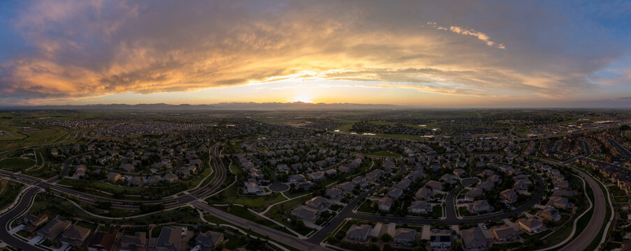 Sunset over mountains on the Front Range in Colorado. Aerial panorama view above large suburban housing developments near Denver in Broomfield, CO.