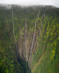 Waimanu Valley waterfalls aerial view on the Big Island, Hawaii. Lush green mountain cliff in...