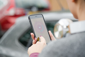 Female runner checking heart rate monitor on smart phone on path