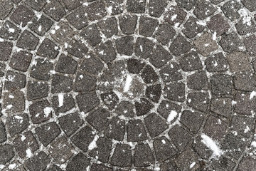 pavement folded in a circle, stone tiles area covered with snow