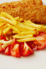 Traditional fish and chips on white plate with fresh cut tomatoes. Simple meal serving. Sea food.