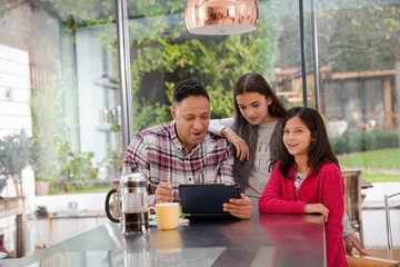 Family using digital tablet at kitchen table