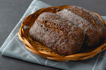 Fresh rye buns in a basket on a wooden table