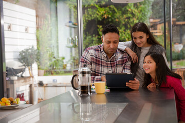 Happy family planning vacation at digital tablet in kitchen