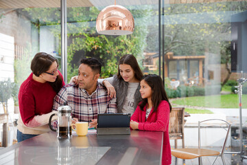 Happy family using digital tablet at kitchen table
