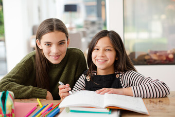 Girl helping young sister with homework