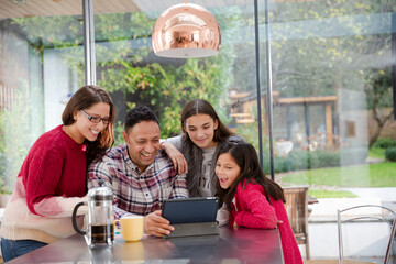 Happy family planning vacation at digital tablet in kitchen