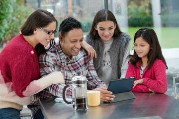 Happy family using digital tablet at kitchen table