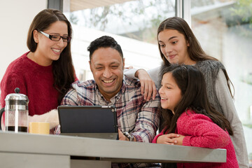 Happy family using digital tablet at kitchen table