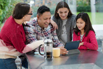 Happy family using digital tablet at kitchen table