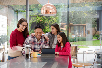 Happy family using digital tablet at kitchen table