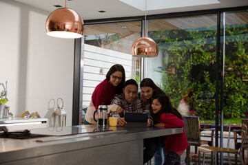 Obraz na płótnie Canvas Happy family using digital tablet at kitchen table