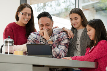 Happy family using digital tablet at kitchen table