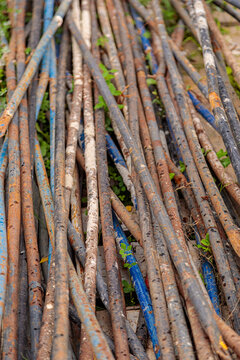 A pile of rusty steel pipes on the ground. Rusty mounting pipes at a construction site.