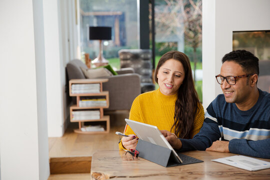 Couple Using Digital Tablet At Kitchen Island