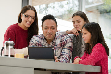 Happy family using digital tablet at kitchen table