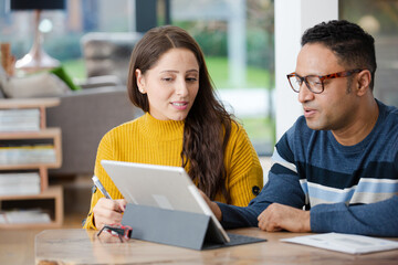 Couple using digital tablet at kitchen island