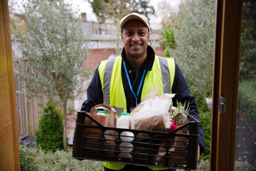 Portrait confident, friendly grocery deliveryman at front door