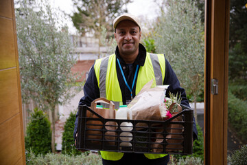 Portrait confident, friendly grocery deliveryman at front door