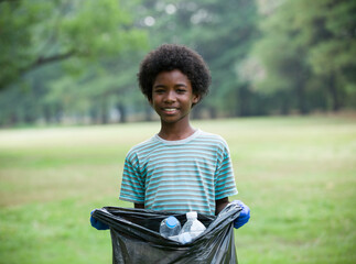 African American smiling boy holding black garbage bag with plastic bottle. Volunteer concept