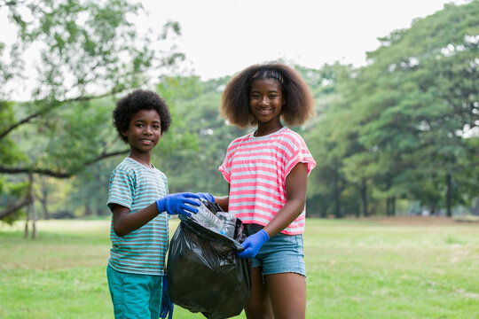 Volunteer children. Cheerful boy and girl in gloves holding black garbage bag with plastic bottles outdoor. Volunteer and charity concept