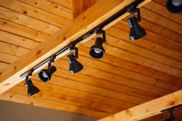 Black LED lights hang on wood beam on ceiling in home, room lighting