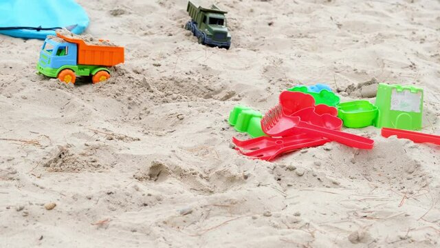 Childrens plastic toys lying on the white sand. Concept for summer games and children occupation