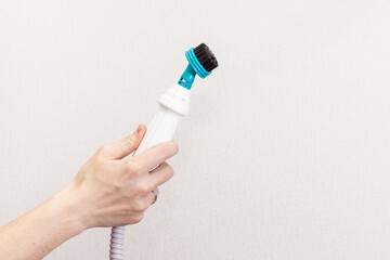 Manual steam cleaner with a brush nozzle. Space for text. Man holds a steam cleaner