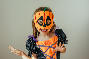 Portrait of little girl dressed Halloween witch costume and pumpkin mask