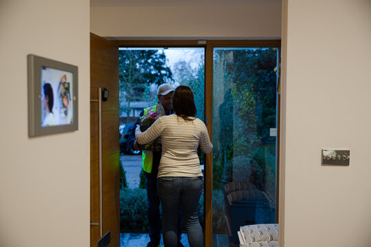 Smiling Woman Receiving Package From Deliveryman At Front Door