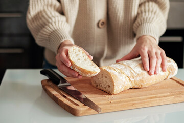 Close-up of a woman cutting bread on a wooden cutting board