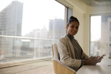 Portrait of smiling businesswoman using smartphone in office