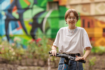 teen girl, brunette with glasses on a scooter, on a city street, on a clear sunny day