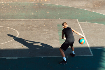 Teenager boy basketball player dribbling on sports ground