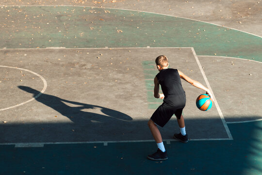 Teenager Boy Basketball Player Dribbling On Sports Ground