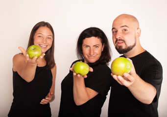 a family with apples in their hands portray funny theatergoers vegetarians for a healthy image of life against meat. The concept of weight loss