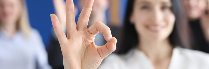 Business woman showing ok gesture on background of colleagues closeup