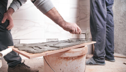 Worker putting tiles adhesive to the wall.