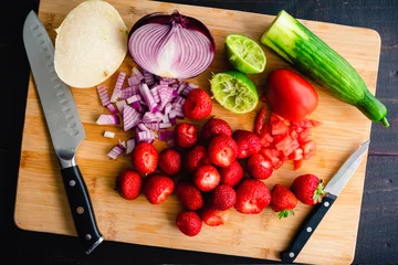 Foto op Canvas Prepping Fruit and Vegetables on a Bamboo Cutting Board: Chopped fruits and vegetables with a santoku knife and a paring knife on a wood background © Candice Bell