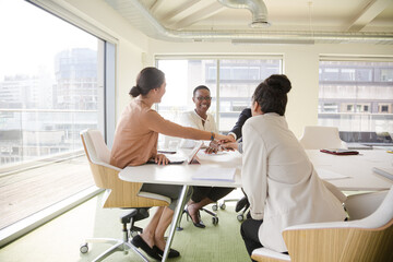 Obraz premium Happy business people touching hands, celebrating success in conference room