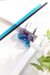 Blue glass earrings and flowers on white background. Natural. Lampwork concept. Modern jewelry