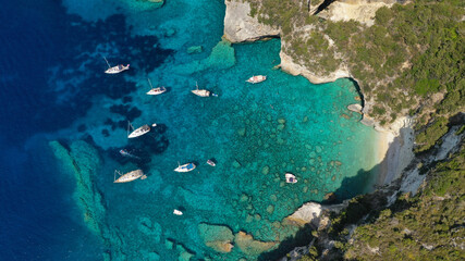 Aerial drone photo of sail boats anchored in tropical Caribbean island paradise bay with white rock caves and turquoise clear sea