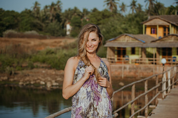 Portrait of a smiling blonde girl in a dress in the summer sun