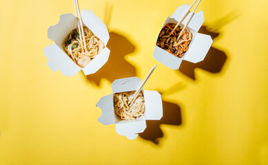 the concept of food delivery on a yellow background . noodles in boxes