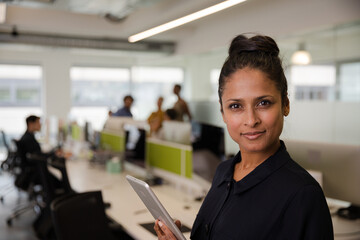 Portrait of confident businesswoman in open plan office