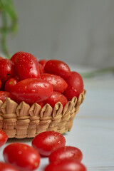Stack of wet cherry tomatoes in a wooden basket, freshly harvested.