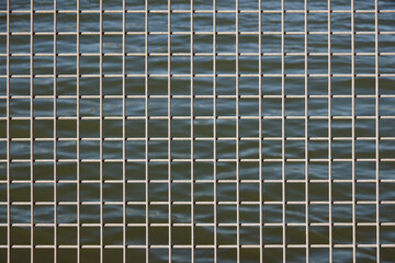 Full frame close-up view of a section of a metal safety fence with ocean water visible behind
