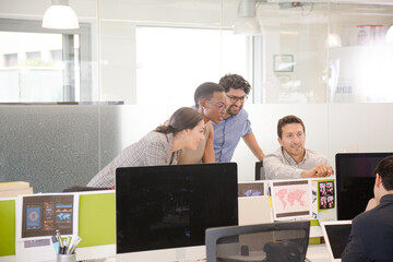 Business people brainstorming at computer in open plan office