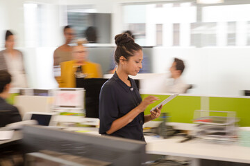 Businesswoman using tablet computer in open plan office