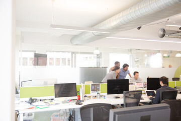 Business people brainstorming at computer in open plan office